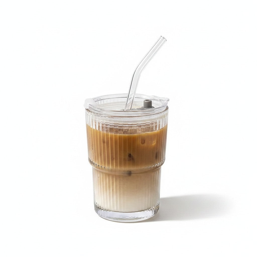 Copo de vidro canelado Cucinamup de 600ml com tampa e canudo, contendo café gelado com leite em fundo branco.