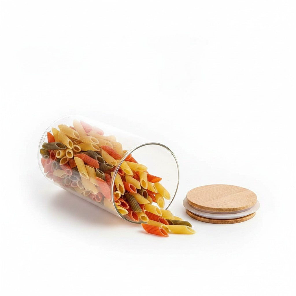 Pote hermético de vidro borossilicato Cucinamup com tampa de bambu e massa penne colorida sobre fundo branco