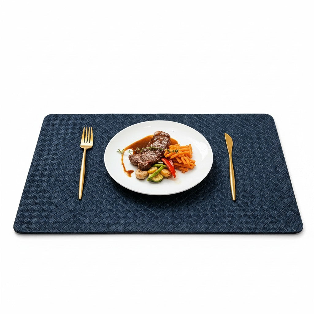 Jogo americano Cucinamup azul marinho trançado em couro sintético com prato de carne e talheres dourados na mesa